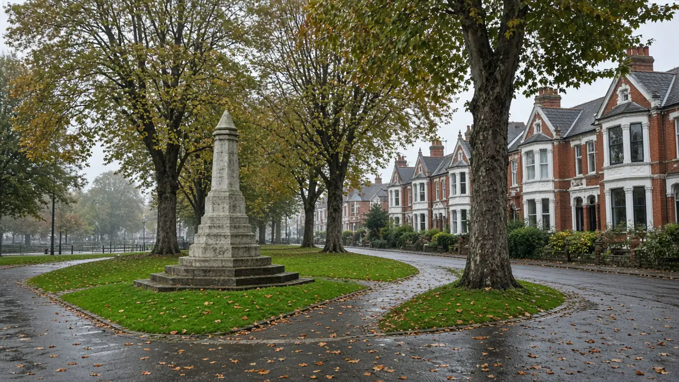 Stone war memorial on a village green with Victorian red-brick villas in a West Sussex town like Haywards Heath